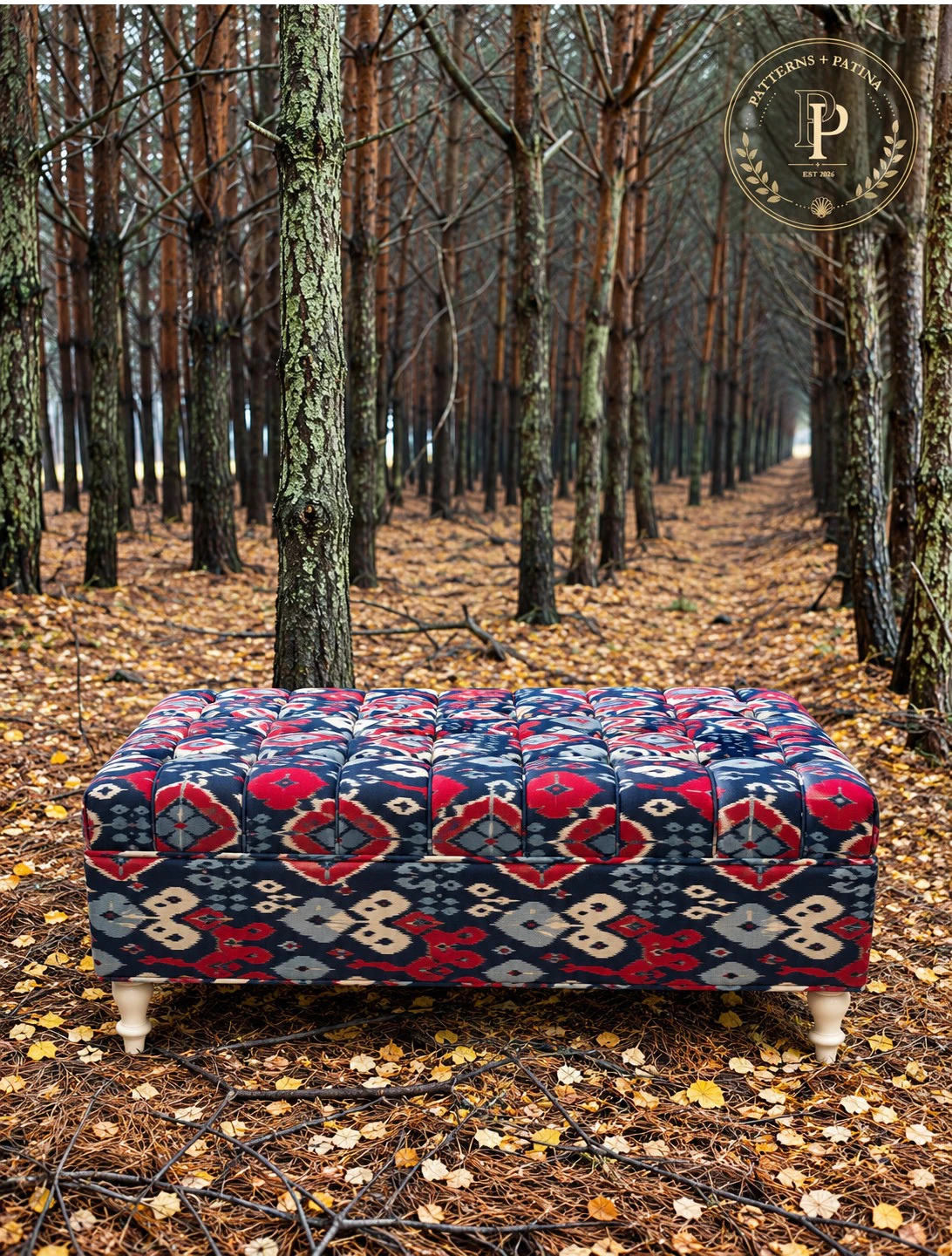 Large tufted ottoman in a navy and red ikat, on a pine forest floor.